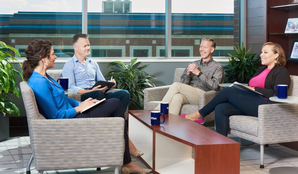 Career and Growth Opportunities at MiTek - Group of MiTek employees sit and have a meeting around a small table