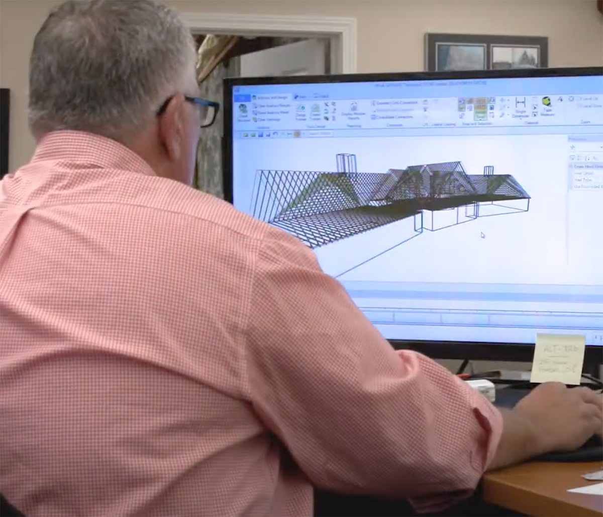 MiTek Design Support Services - Man sitting at desk working at computer with 3D model on the display