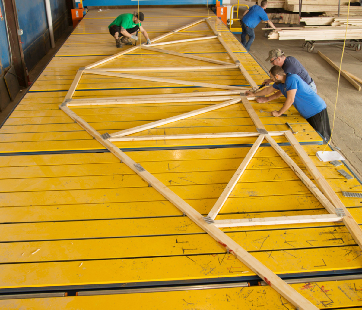 MiTek PDS Ready Table Automated Solutions - Four men aligning wooden truss on ready table