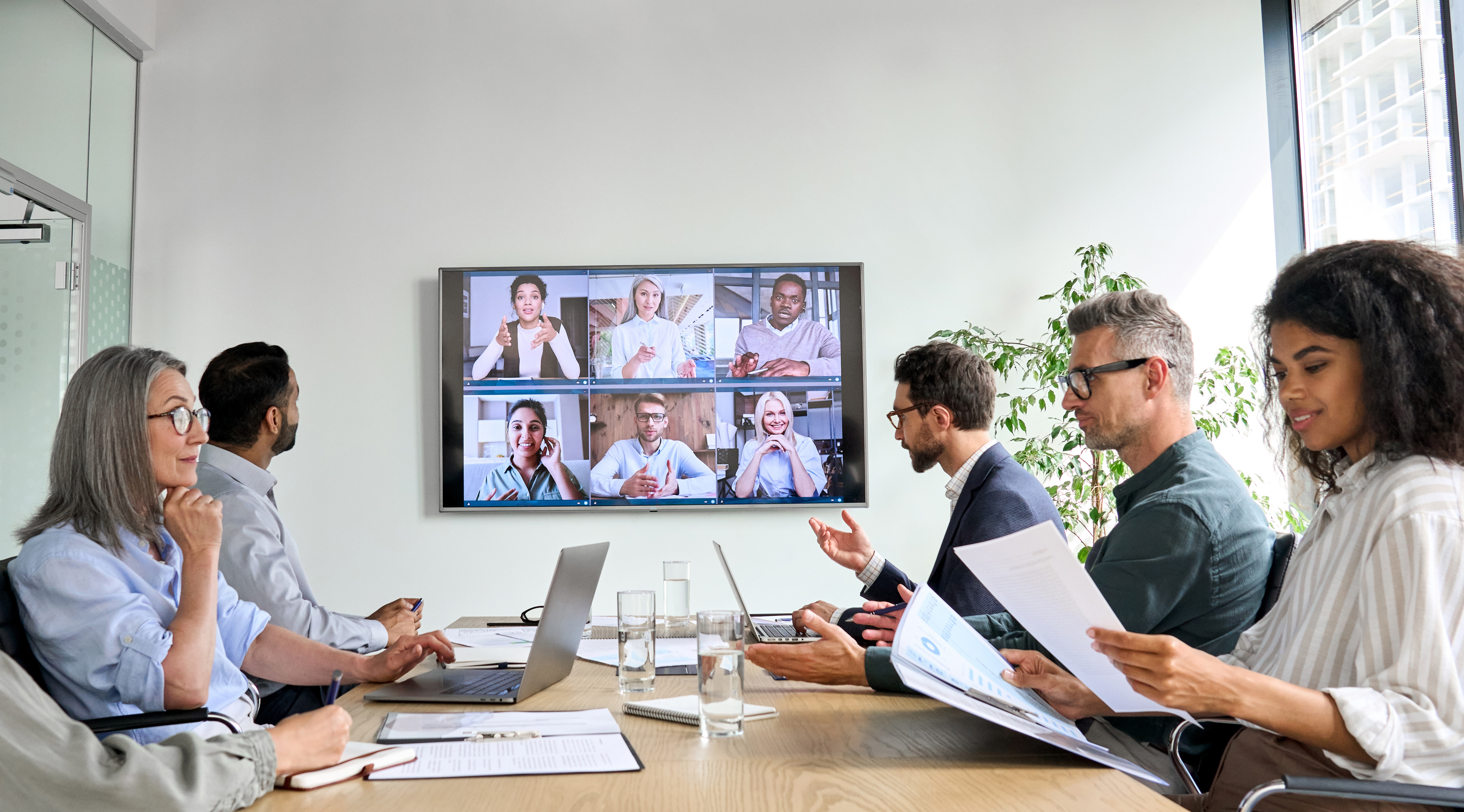 A group of employees having a hybrid conference call in a meeting room